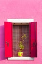 Pink painted facade of the house and window with red shutters Royalty Free Stock Photo