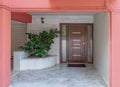 Pink painted portico of an apartment building entrance covered with white marble, potted plants and a dark wood door. Royalty Free Stock Photo