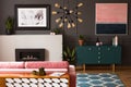 Pink painting above green cabinet in grey flat interior with fireplace in front of couch