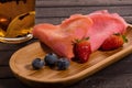 Pink pancakes with blueberries and strawberries on a wooden plate Royalty Free Stock Photo