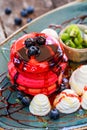 Pink pancakes with honey, chocolate, jam, whipped cream, berries and fruits on plate. Royalty Free Stock Photo