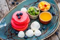 Pink pancakes with honey, chocolate, jam, whipped cream, berries and fruits on plate. Royalty Free Stock Photo