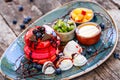 Pink pancakes withaPink pancakes with honey, chocolate, jam, whipped cream, berries and fruits on plate. Royalty Free Stock Photo