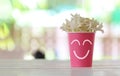 Pink paper cup with a smile symbol and white flowers blooming on top cup Royalty Free Stock Photo