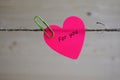 Pink paper in the form of heart is attached by paper clip to a rope Royalty Free Stock Photo