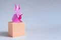 Pink paper hare on an orange cube on a light background. Royalty Free Stock Photo