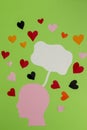 pink paper head with white bubble above as copy space and colorful hearts around, on green background Royalty Free Stock Photo