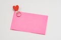 Pink paper notes fastened with a wooden clothespin in heart form on a white background Royalty Free Stock Photo