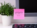 A pink paper notes with the reminder Update on it sticked on to a monitor at an office workplace Royalty Free Stock Photo