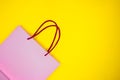 Pink paper shopping bag on yellow background. Black Friday sale shopping. Royalty Free Stock Photo