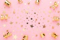 Pink pastel festive flatly. Many sparkling golden confetti and ribbons scattered at pink background. Festive concept