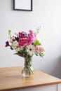 Pink and pastel white flowers in Modern glass vase on wooden table on gray wall background Royalty Free Stock Photo