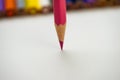 Pink pencil on a blurry background of colored pencils aimed at white paper vertically Royalty Free Stock Photo