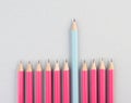 Pink pencils in a row, one blue pen is standing out, be different, leadership and teamwork concept Royalty Free Stock Photo