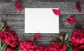 Pink peonies flowers and sheet of paper over dark wooden background with space for text Royalty Free Stock Photo