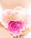 Pink peonies in woman`s hands. Elegant bunch of beautiful flowers, soft white background, shallow dof.