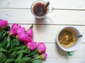 pink peony flowers, a cup of tea and a cup of coffee on white boards