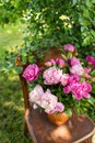 Pink peony in a jug on an old vintage wooden chair, rustic still life. A bouquet for a wedding or birthday.