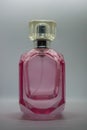 A pink perfume bottle with a silver cap lies on a white surface Royalty Free Stock Photo