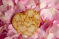 Pink petals with droplets and wooden heart shape with love text Royalty Free Stock Photo