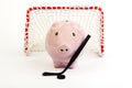 Pink piggy bank with black hockey stick and black hockey puck and red hockey gate with white net on white background Royalty Free Stock Photo