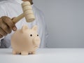 Pink piggy bank and businessman man hand is holding a wooden hammer to smashing for getting the money on table. Royalty Free Stock Photo