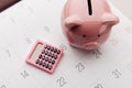 Pink piggy bank and calculator on a white calendar background, saving and investment concept. Top view Royalty Free Stock Photo
