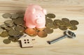 Pink Piggy bank ,coins,key and symbol house on wooden background. Property concept. Royalty Free Stock Photo