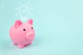 Pink piggy bank with digital hologram light bulp on blue background. Bussiness innovation, brainstorming, inspiration and solution