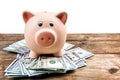Pink piggy bank on dollars on wooden background