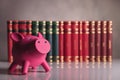 Pink piggy bank in front of a row of books Royalty Free Stock Photo