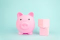 Pink piggy bank with geometric wood blocks cube on blue background