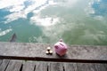 Pink piggy bank and gold coin pile on brown wooden with water and clouds background, step up growing business to success and Royalty Free Stock Photo