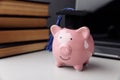 Pink piggy bank in hat with books close-up. College, graduate, education concept Royalty Free Stock Photo