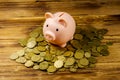 Pink piggy bank on a heap of coins on wooden background. Saving money concept Royalty Free Stock Photo