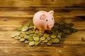 Pink piggy bank on a heap of coins on wooden background. Saving money concept Royalty Free Stock Photo