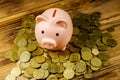 Pink piggy bank on a heap of coins on wooden background. Saving money concept Royalty Free Stock Photo