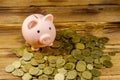 Pink piggy bank on a heap of coins on wooden background. Saving money concept Royalty Free Stock Photo