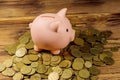 Pink piggy bank on a heap of coins on wooden background. Saving money concept Royalty Free Stock Photo