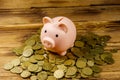 Pink piggy bank on a heap of coins on wooden background. Saving money concept Royalty Free Stock Photo