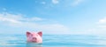 Pink piggy bank sinking in blue water, symbolizing debt, bankruptcy, and loss of money with blue sky Royalty Free Stock Photo