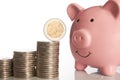 Pink piggy bank and stack of coins growing up with two euro coin Royalty Free Stock Photo