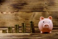 Pink piggy bank and stacks of coins on wooden background. Saving money concept Royalty Free Stock Photo