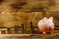 Pink piggy bank and stacks of coins on wooden background. Saving money concept Royalty Free Stock Photo