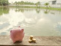 Pink piggy bank standing on wooden with gold coins pile and water background, Saving money for future plan and retirement fund Royalty Free Stock Photo