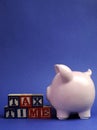 Pink piggy bank with Tax Time message on building blocks for Tax Day or End of Financial Year - vertical with copy space. Royalty Free Stock Photo