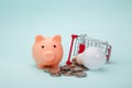Pink piggy bank, trolley and light bulb on blue background, power savings concept Royalty Free Stock Photo