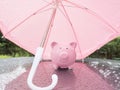 Pink Piggy bank with umbrella On a rainy day Saving money for any storm problem will come concept for finance, insurance, Royalty Free Stock Photo