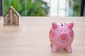 Pink piggy bank on wooden desk - save money to buy house concept Royalty Free Stock Photo