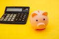 Pink piggy or coin bank or piggybank or money box and calculator - finance and savings concept on yellow background Royalty Free Stock Photo